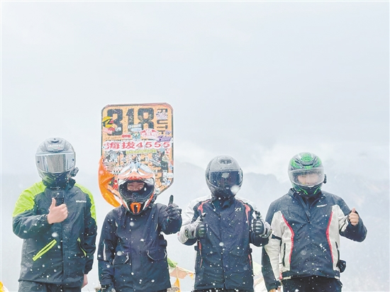 餘鴻威（右一(yi)）與“旅遊搭子(zi)”騎摩托車(che)到(dao)西藏途中(zhong)郃(he)影留念。